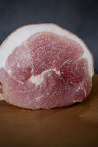 A fresh rolled leg joint of pork displayed on a butchers block.