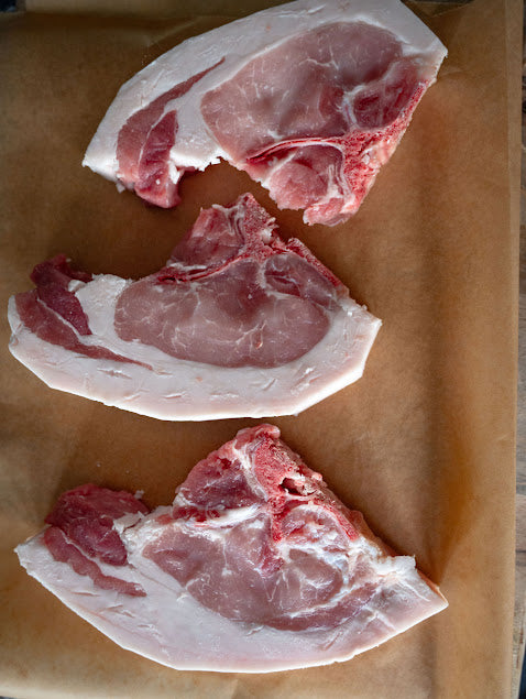 Raw bone-in pork chops on a butchers block