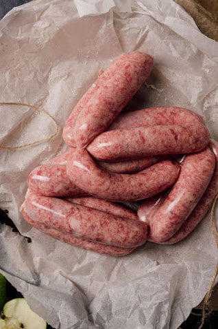 A photo of several link sausages made from Mangalitza pork and black pepper, resting on a piece of butcher paper.