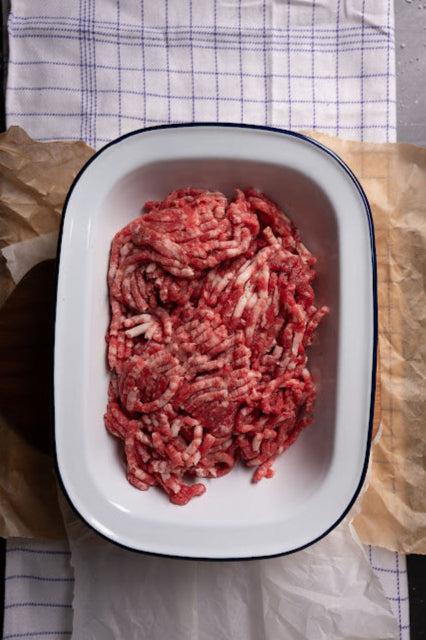 A bowl of minced lamb in a tin tray on a checkered tablecloth.