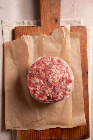 Raw lamb burger on brown paper on a wooden cutting board